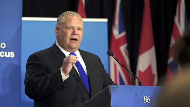 Photo de Doug Ford au podium portant une cravate bleue. Photo de Doug Ford au podium portant une cravate bleue.