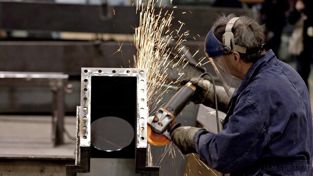 Un homme usine une pièce de métal.