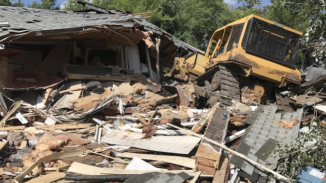 Un bulldozer est garé au-dessus des restes de la maison complètement détruite. Un bulldozer est garé au-dessus des restes de la maison complètement détruite.