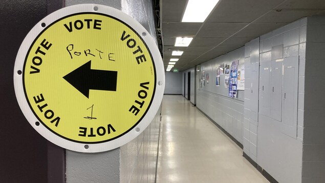 Une affiche avec une flèche qui pointe à gauche pour indiquer la direction du bureau de vote.