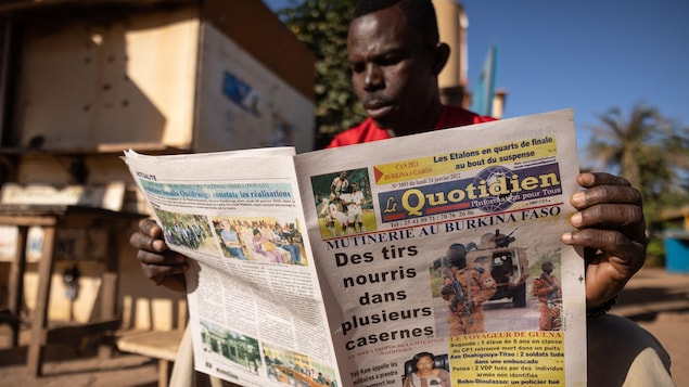 Un homme lit un journal. En une, on peut lire « Mutinerie au Burkina Faso : des tirs nourris dans plusieurs casernes ».