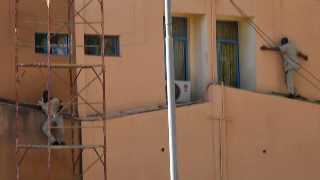 Un homme longe le mur extérieur du quartier général de l'armée, un autre s'est réfugié sur un échafaudage. Un homme longe le mur extérieur du quartier général de l'armée, un autre s'est réfugié sur un échafaudage.