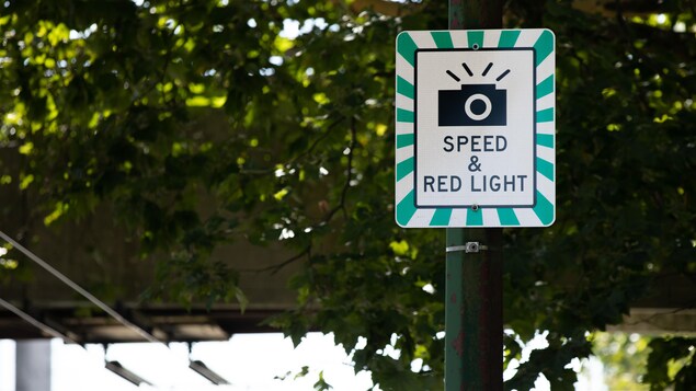 Un panneau de signalisation indique qu'une caméra surveille l'intersection.