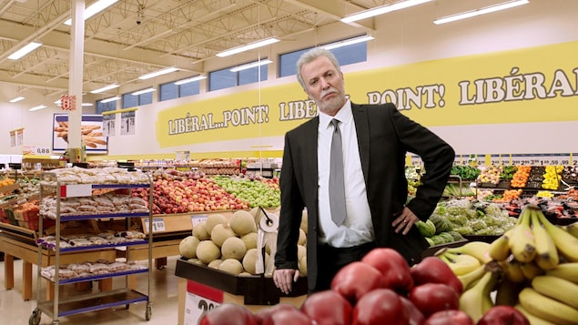 Un homme se tient debout en costume dans le rayon fruits et légumes d'une épicerie. Un homme se tient debout en costume dans le rayon fruits et légumes d'une épicerie.