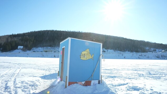 Une cabane à pêche bleu avec un dessin de poisson jaune.