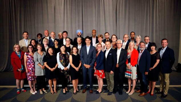Les ministres se tiennent debout autour de Justin Trudeau.