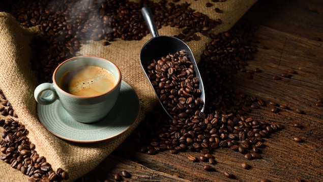 Une tasse et des grains de café reposent sur un plancher en bois.