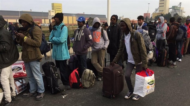 Des migrants font la file pour monter dans les autobus. Des migrants font la file pour monter dans les autobus.