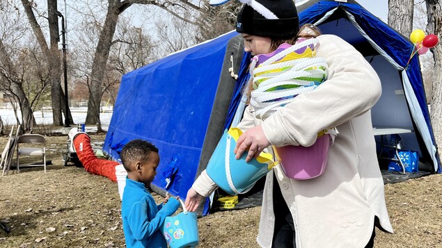 Un jeune enfant reçoit un panier pour ramasser des œufs de Pâques.
