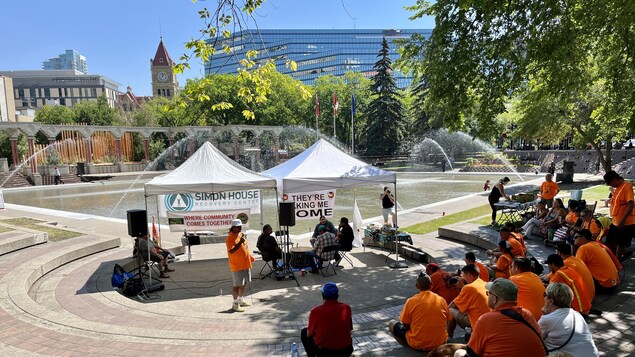 Des personnes sont assises dans un espace extérieur où des tentes ont été installées au centre-ville de Calgary.