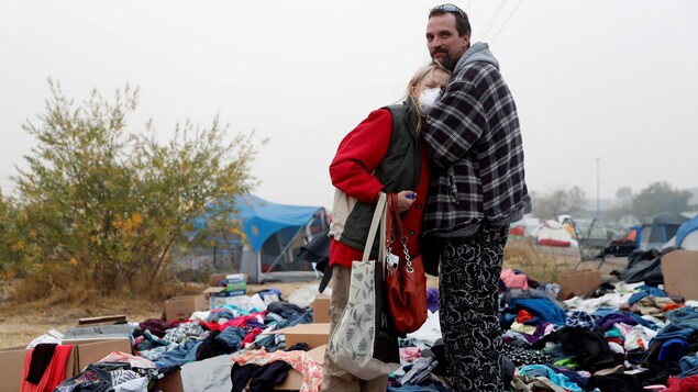 Des évacués debout dans un stationnement jonché de vêtements et d'objets. Des évacués debout dans un stationnement jonché de vêtements et d'objets.