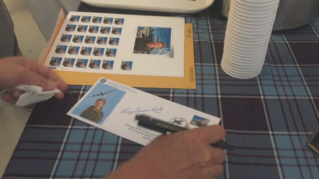 Mary Cameron-Kelly signe un autographe sur le document Mary Cameron-Kelly signe un autographe sur le document