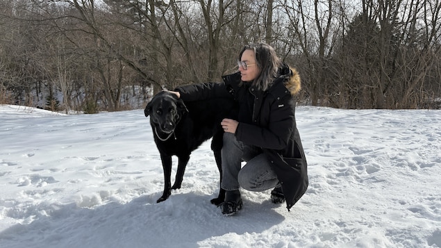 Camille Gallard est assise à côté de Cookie dans la neige. 