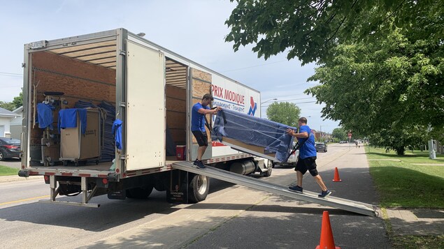 Les déménageurs portent un meuble vers un camion. 