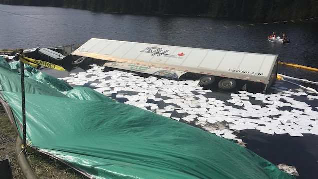 Un barrage antipollution entoure un camion tombé dans un lac. Un barrage antipollution entoure un camion tombé dans un lac.