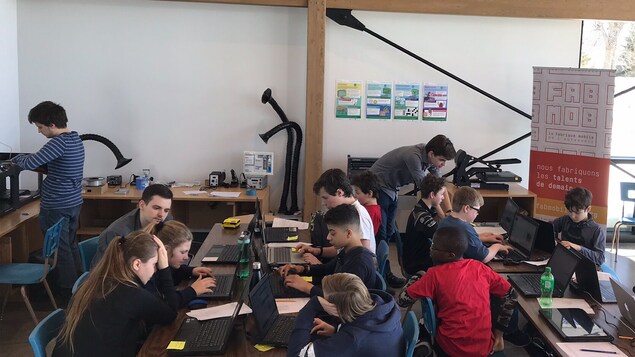 Deux groupes de jeunes travaillent sur des ordinateurs.