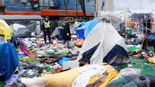 Le camp de tentes montées sur un terrain, entourées de nombreux détritus. Le camp de tentes montées sur un terrain, entourées de nombreux détritus.