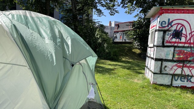 Une tente et une cabane de fortune dans un parc.