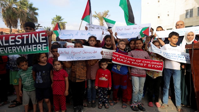 Des dizaines de Gazaouis tiennent des affiches.
