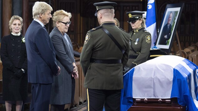 Un cercueil recouvert d'un drapeau, flanqué de deux policiers. Un cercueil recouvert d'un drapeau, flanqué de deux policiers.