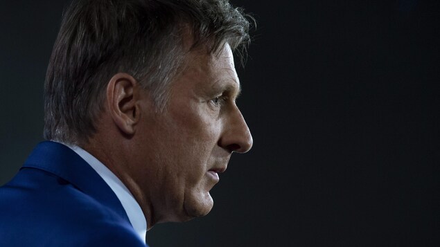 Maxime Bernier, de profil, l'air sérieux, photographié du niveau des épaules jusqu'au haut de la tête.