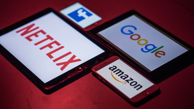 Logo ng Facebook, Netflix, Google at Amazon sa mga screen ng smartphones at iPad.