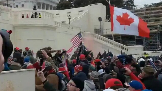Des personnes tiennent un drapeau canadien lors des émeutes du Capitole de Washington le 6 janvier.