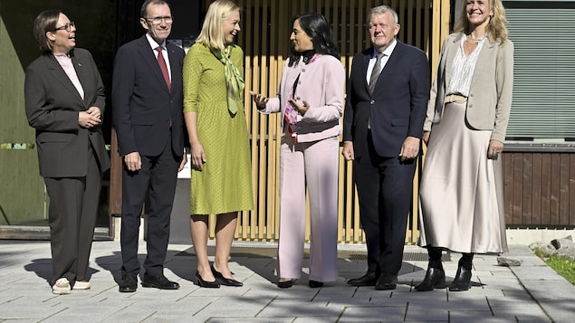 A group of six men and women stand together outside. 