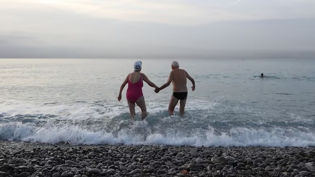 An elderly man and woman hold hands as they walk into the sea in this 2016 file photo. Canadians are getting fewer divorces, according to a new report. But they're also less likely to get married at all. 