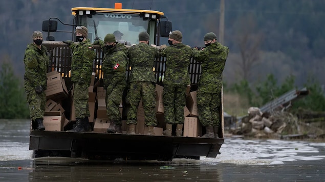 Members of the Canadian Forces arrive by front end loader to help residents cope with catastrophic flooding in Abbotsford, B.C. on November 20, 2021. Climate-driven weather events are part of the array of new threats Canada needs to incorporate into its national security strategy, experts say.