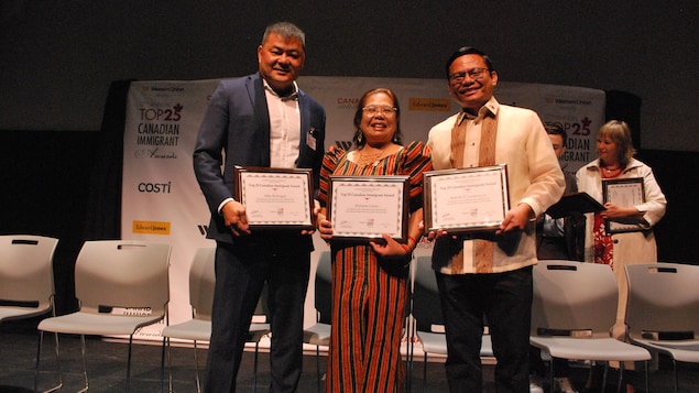 Mga Pilipino na hawak ang kanilang award sa entablado.