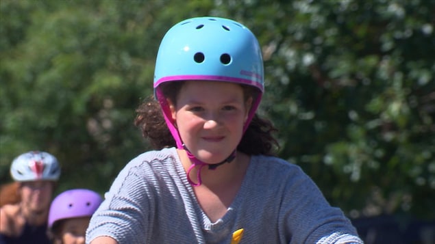 Une jeune fille portant un casque circule à vélo.