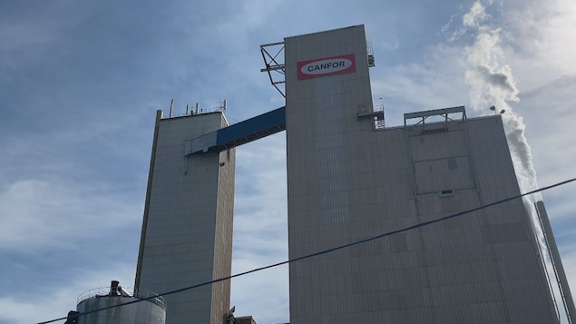 Une usine avec le logo de Canfor par laquelle de la fumée sort.