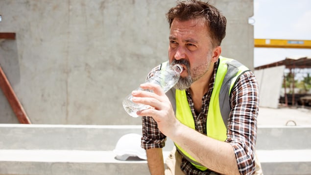 Un travailleur bois de l'eau durant une journée très chaude.