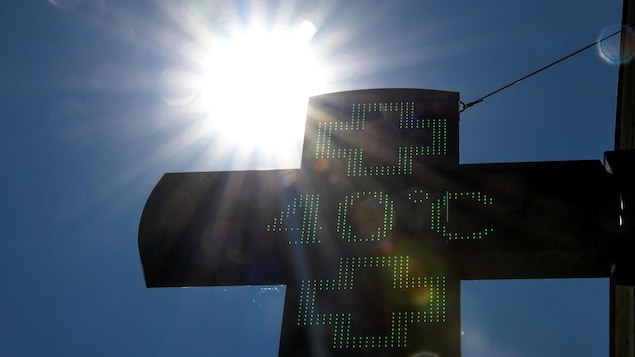 Un panneau numérique indique 40 degrés Celsius devant des rayons du soleil dans un ciel bleu clair. Un panneau numérique indique 40 degrés Celsius devant des rayons du soleil dans un ciel bleu clair.