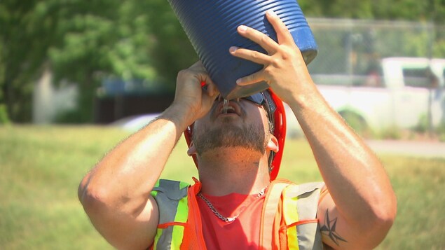 Un travailleur de la construction boit de l'eau.