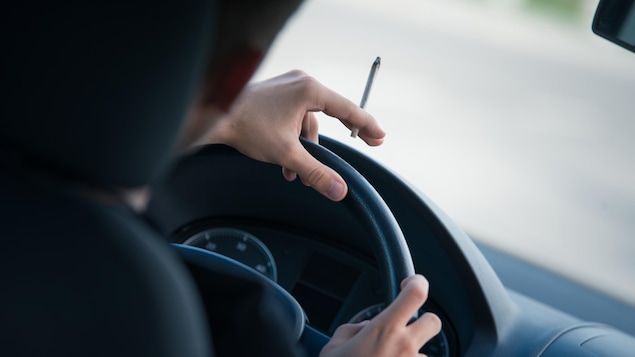 Un conducteur fume un joint au volant d'une voiture.