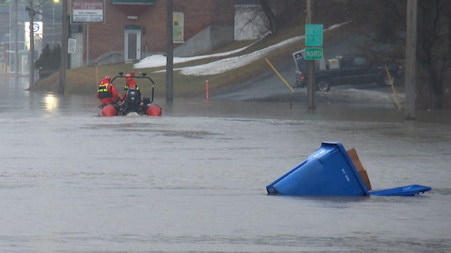 Un canot pneumatique circule devant un bac de récupération qui flotte. 