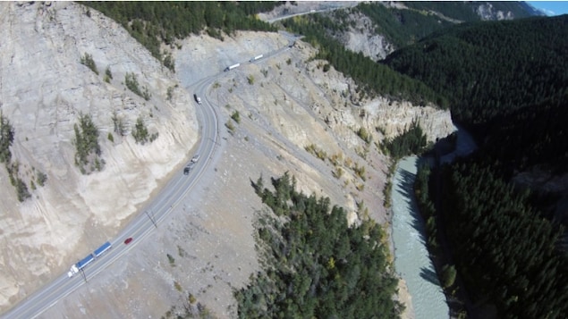 Des voitures circulent sur une route du canyon Kicking Horse dans les Rocheuses canadiennes.