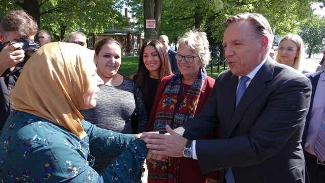 Entourés, le chef de la Coalition avenir Québec serre la main d'une électrice.