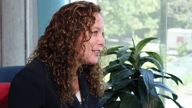 Une femme aux cheveux frisés est vue de profil et elle regarde droit devant elle. Elle a la bouche ouverte et semble esquisser un sourire. Une femme aux cheveux frisés est vue de profil et elle regarde droit devant elle. Elle a la bouche ouverte et semble esquisser un sourire.