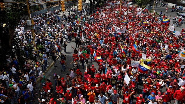 Dans ce secteur de la capitale, des partisans du président Maduro, vêtus de rouge, défilent sous le regard d'opposants. Dans ce secteur de la capitale, des partisans du président Maduro, vêtus de rouge, défilent sous le regard d'opposants.
