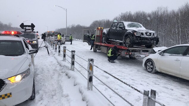 Un véhicule accidenté sur une remorque, près de plusieurs véhicules de la police.