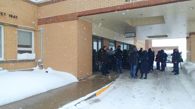 Un groupe de gens devant les portes de l'hôpital