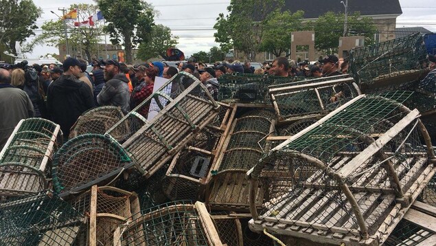 Des centaines de manifestants derrière un mur de casiers à homard vides Des centaines de manifestants derrière un mur de casiers à homard vides