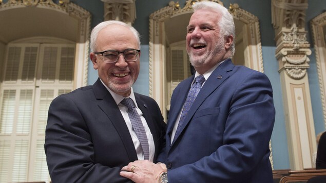 Carlos Leitao et Philippe Couillard se serrent la main en riant à l'Assemblée nationale.