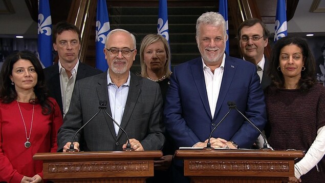 Les sept politiciens sont debout derrière deux lutrins. Les sept politiciens sont debout derrière deux lutrins.