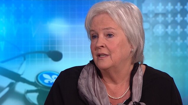 Plan moyen de Carole Trempe devant un décor de fleurs de lys. Plan moyen de Carole Trempe devant un décor de fleurs de lys.