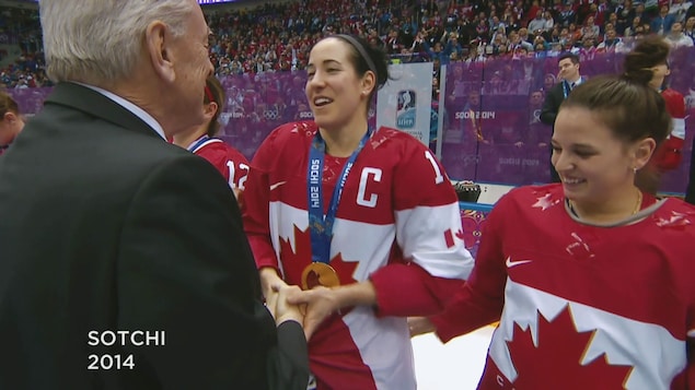 Caroline Ouellette serre la main d’un représentant olympique après qu’il lui ait mis la médaille d’or au cou.