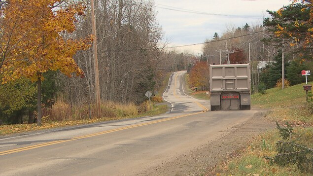 Un camion lourd circule dans un chemin résidentiel.